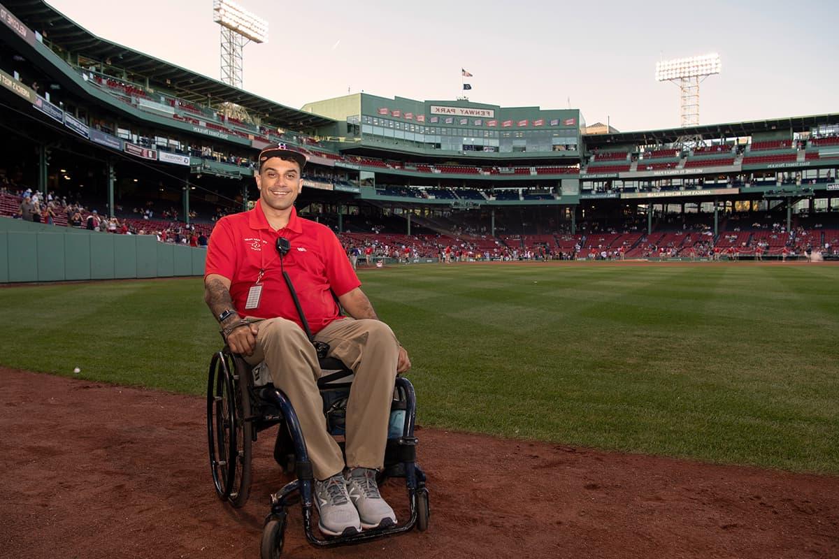 Sitting in his wheelchair on the field at Fenway park, Stefan wears a Red Sox employee shirt.